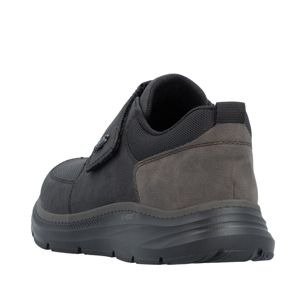 Chaussure basse homme Scratch Semelle souple Sneakers Simili cuir RIEKER B1854 Coloris noir. Vue de biais de l'arrière d'une tennis gauche montrant l'empiècement marron au niveau du talon.